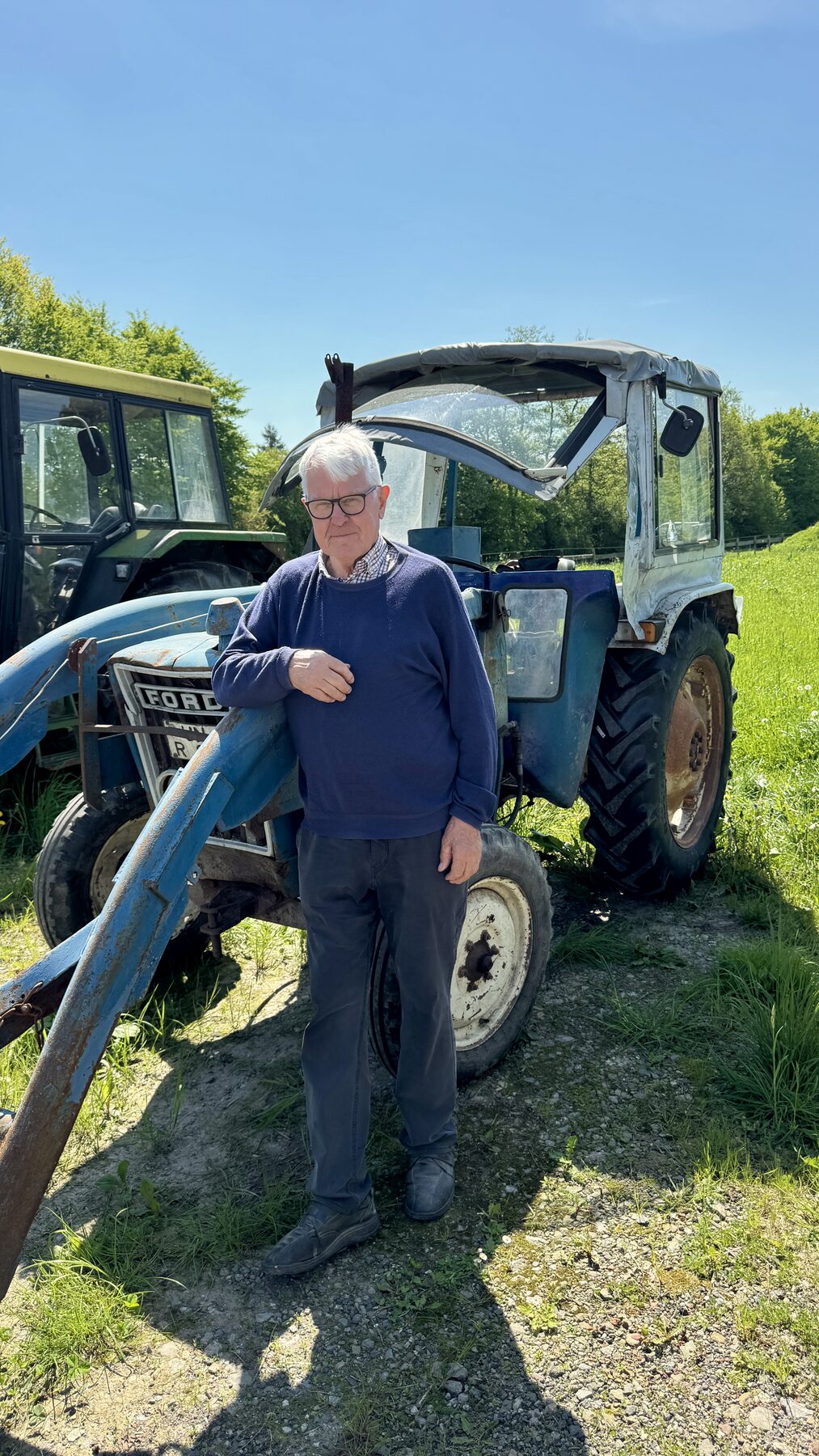 Heiner Duhme lehnt an einem alten Traktor auf dem Hof